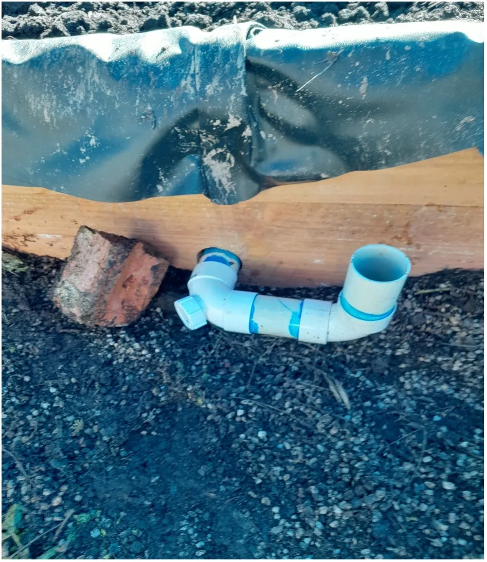 A 45 degree DWV bend joined to a right-angle bend and a short jump-up pipe against the timber wall